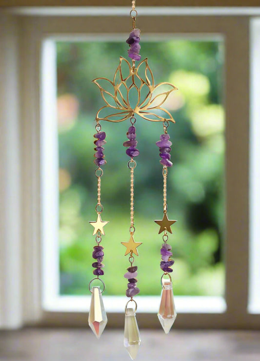Decorative suncatcher hanging in front of window with gold lotus design and purple amethyst crystals